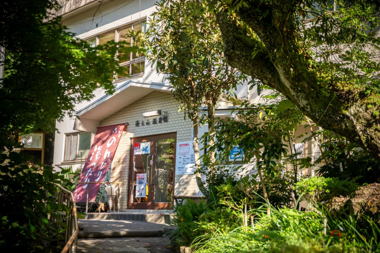 湯の山温泉館の外観。木造の趣ある建物が自然に囲まれている。