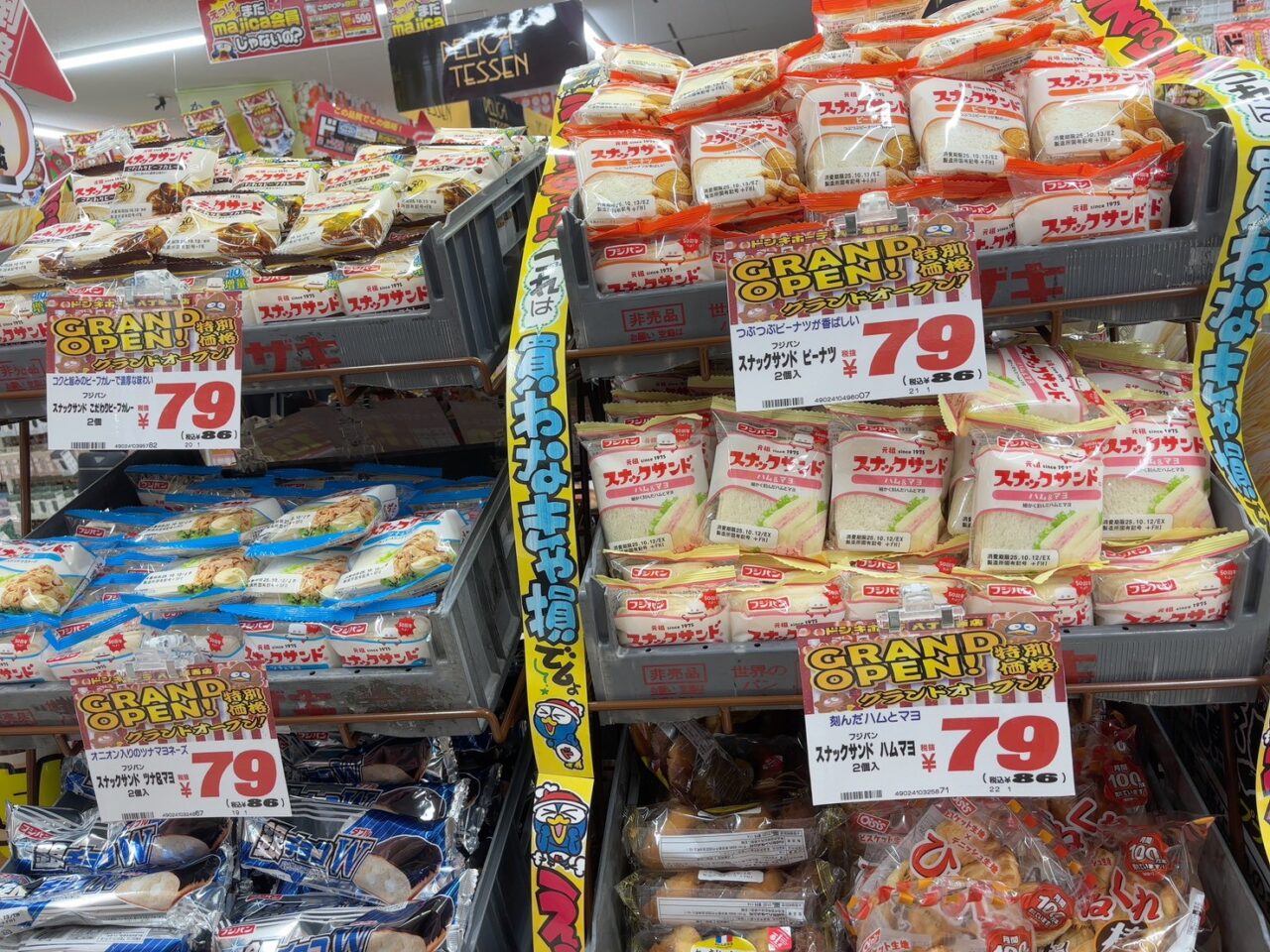 グランドオープン特価で並ぶお買い得おやつコーナー。多くの人が手に取っている様子。