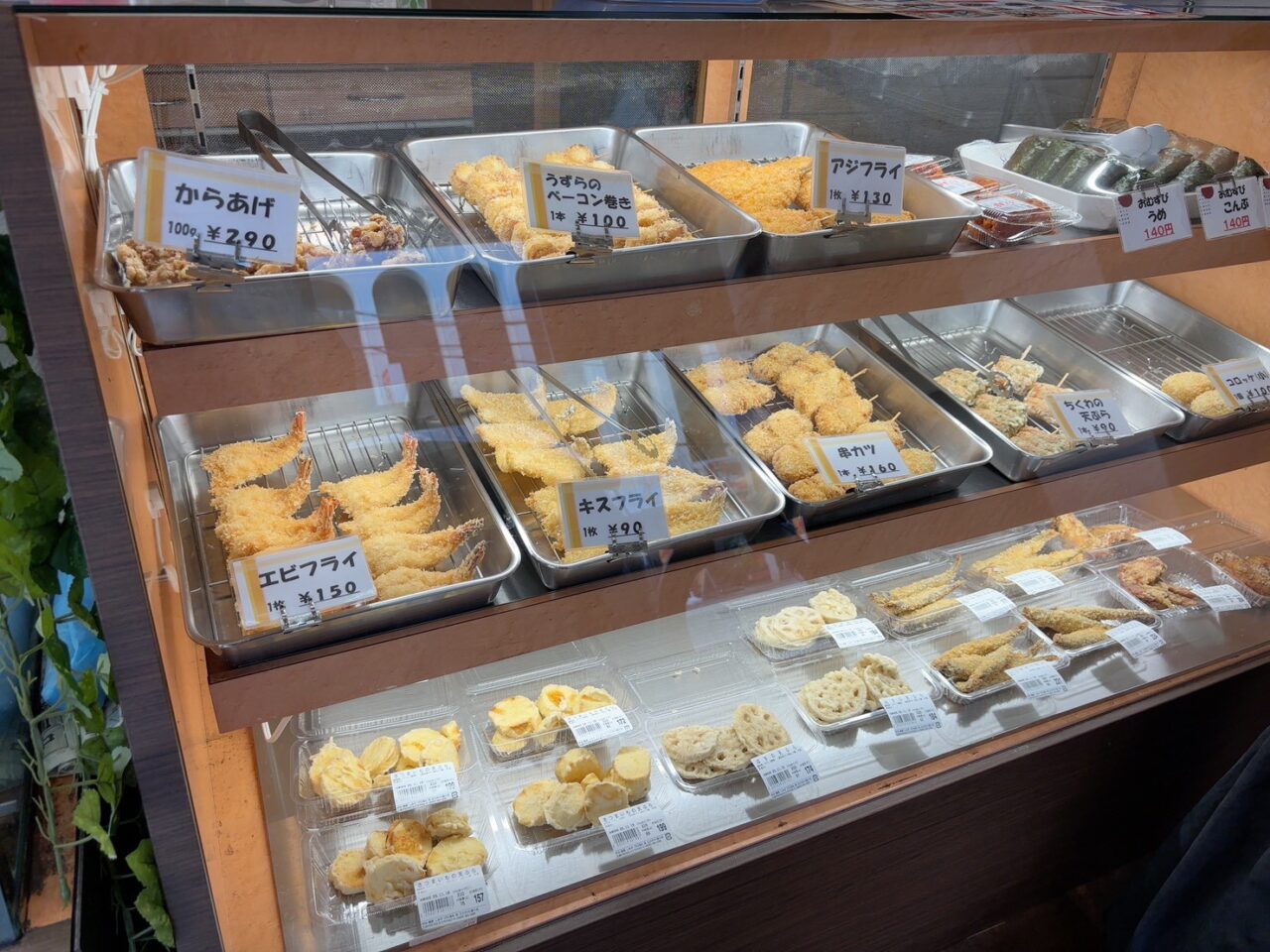 お惣菜が並ぶショーケースの様子。揚げ物や手作り惣菜がずらりと並んでいる