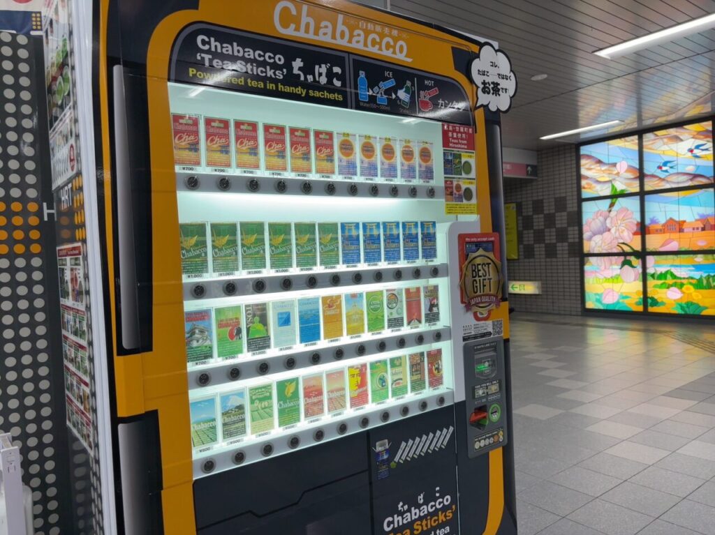 アストラムライン本通駅改札前に設置されたChabaccoのお茶の自動販売機と商品パッケージの様子